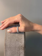 PAIGEAVERI white gold hinged diamond eternity ring with brilliant-cut diamonds, shown on a thumb.